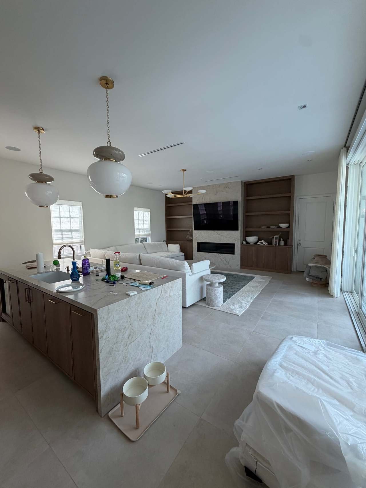Open kitchen with waterfall island, globe pendants and wood cabinetry