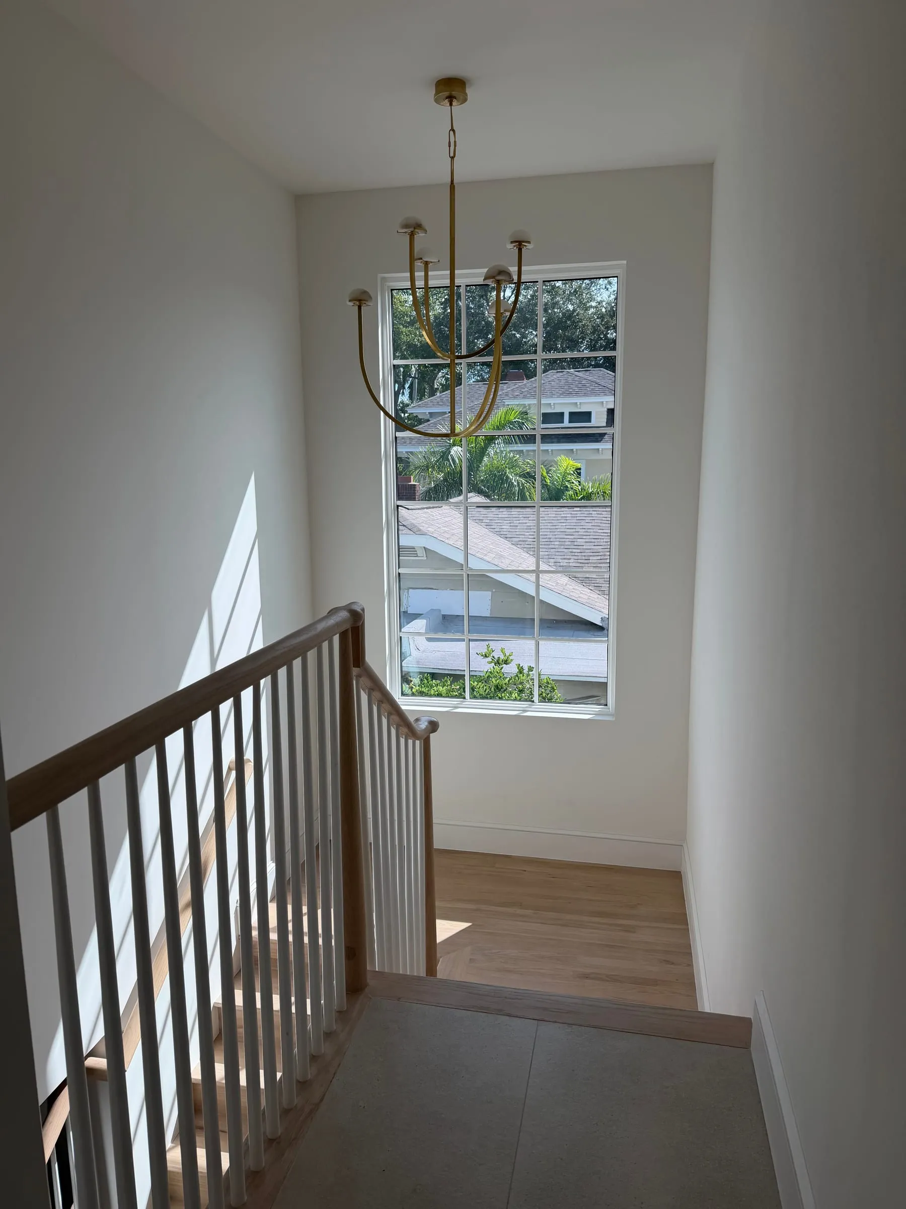 Stair landing with chandelier and tall window