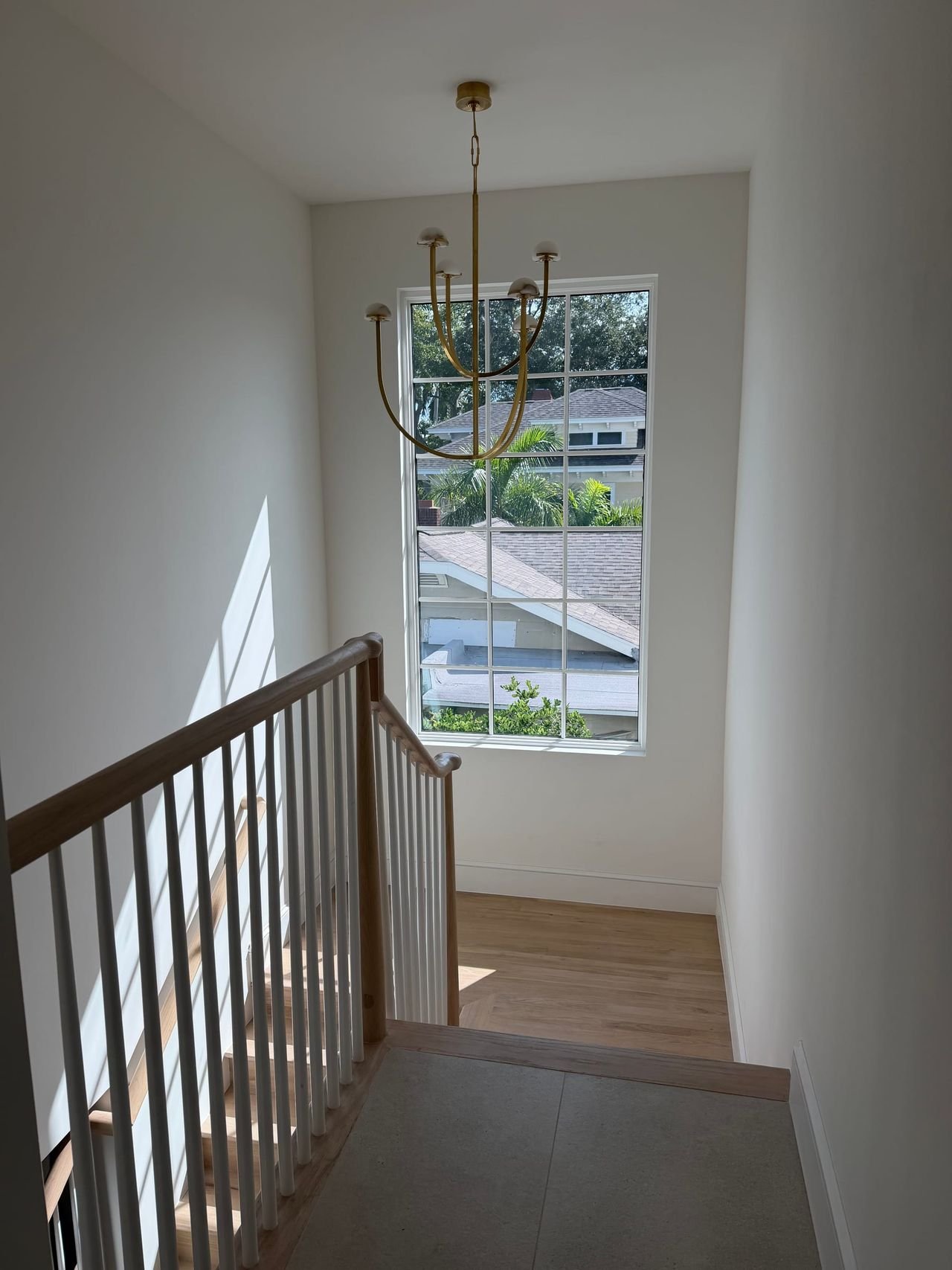 Stair landing with chandelier and tall window