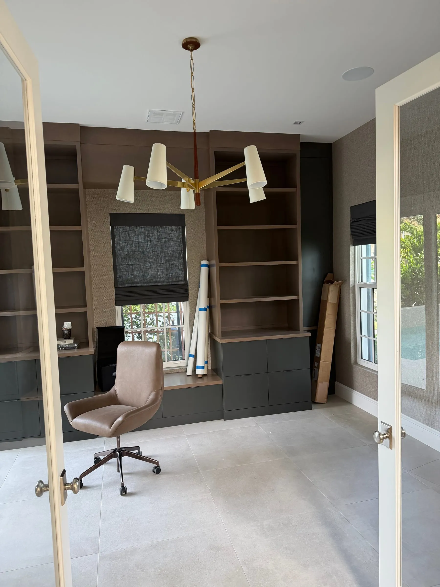 Home office with custom built-in shelving and brass chandelier