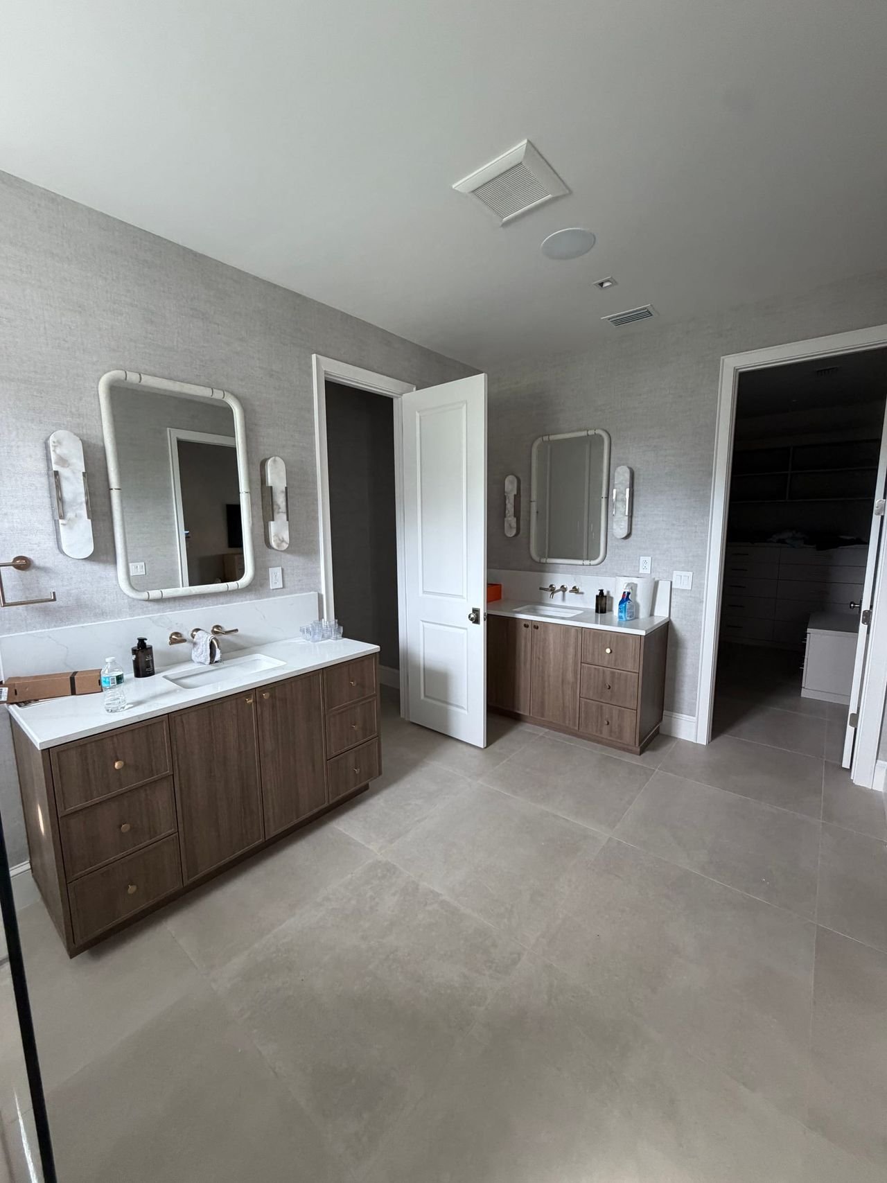 Primary bath with double vanity and walk-in closet beyond