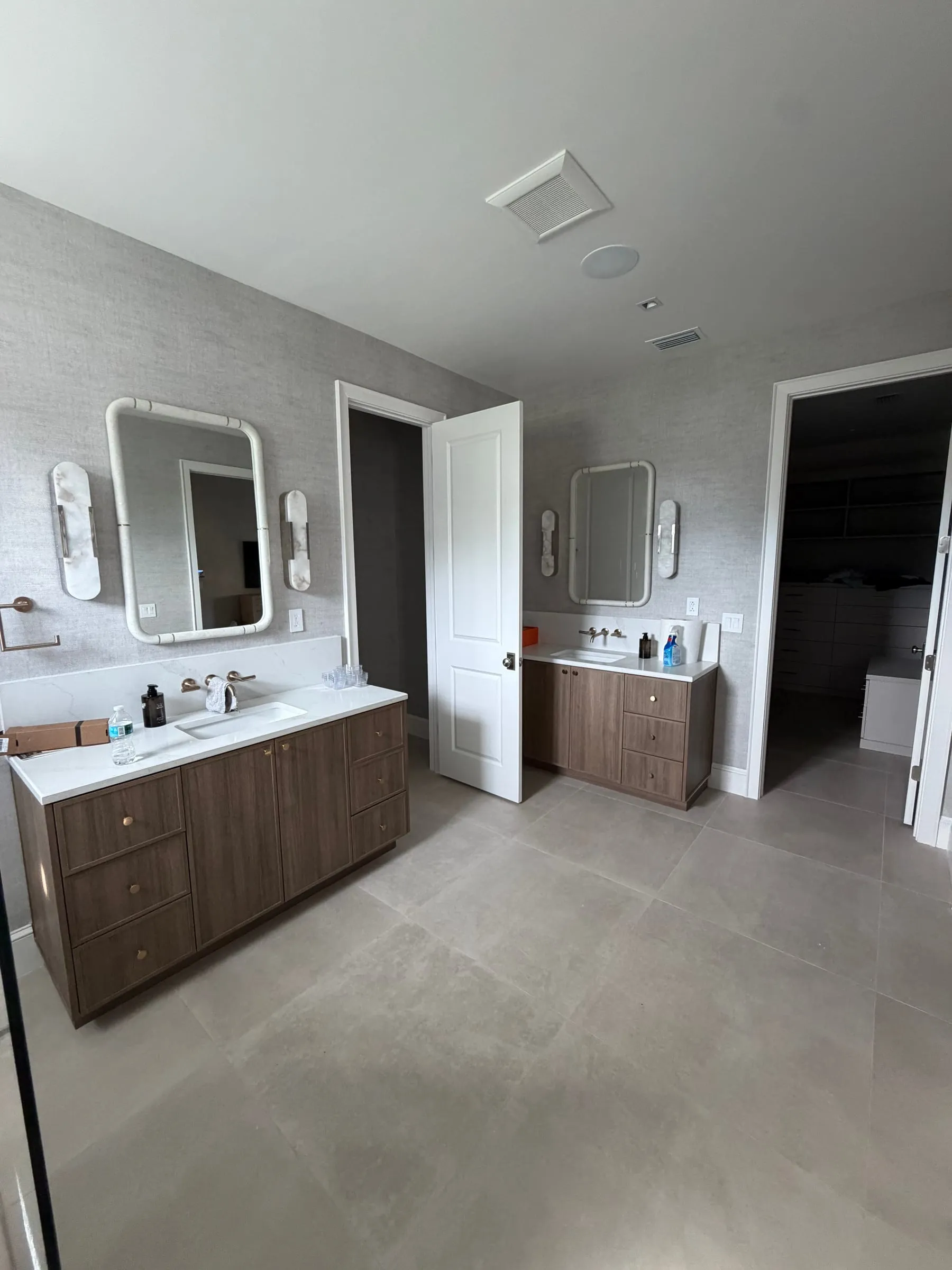 Primary bath with double vanity and walk-in closet beyond