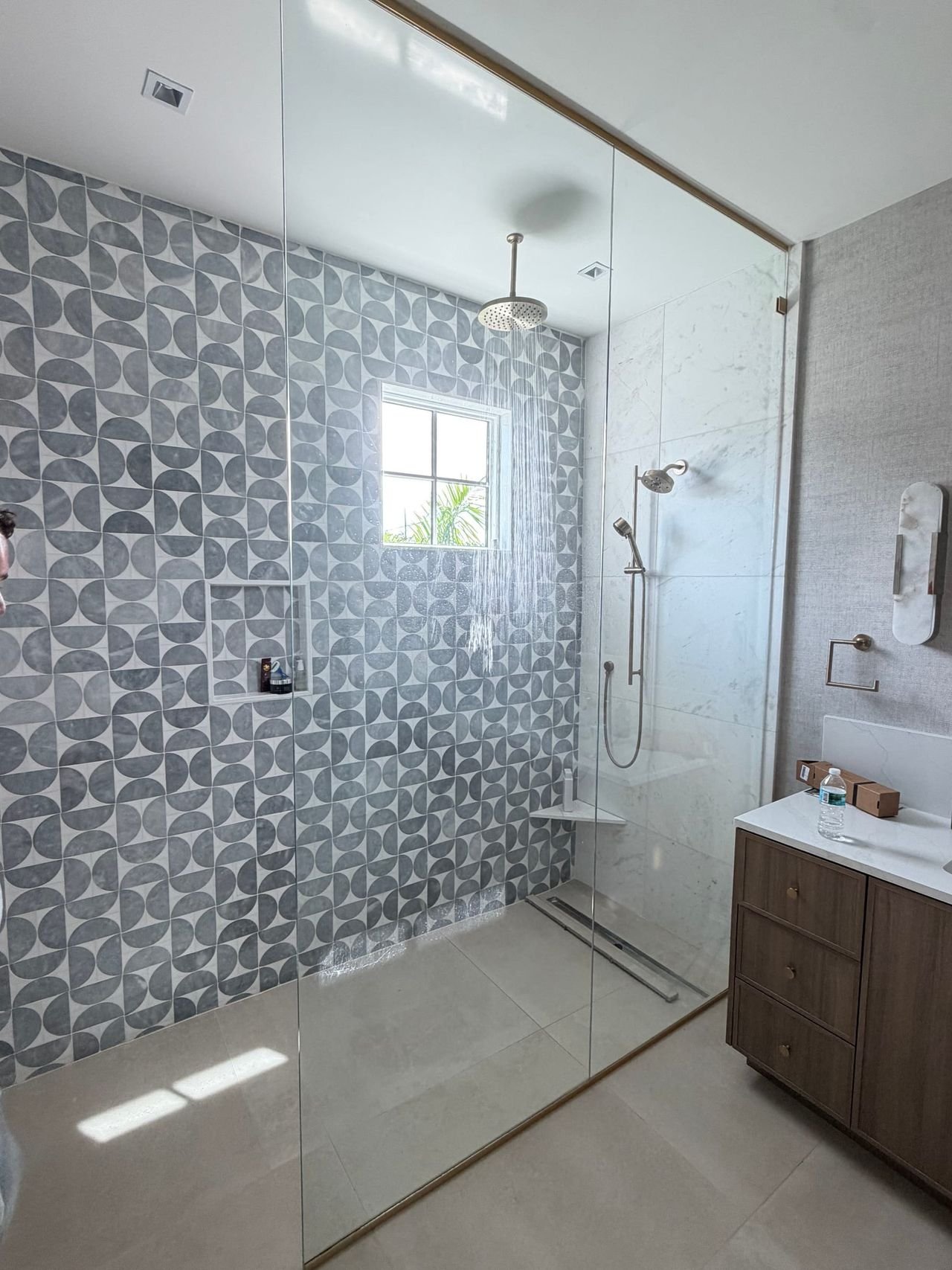 Curbless walk-in shower with patterned tile and glass enclosure